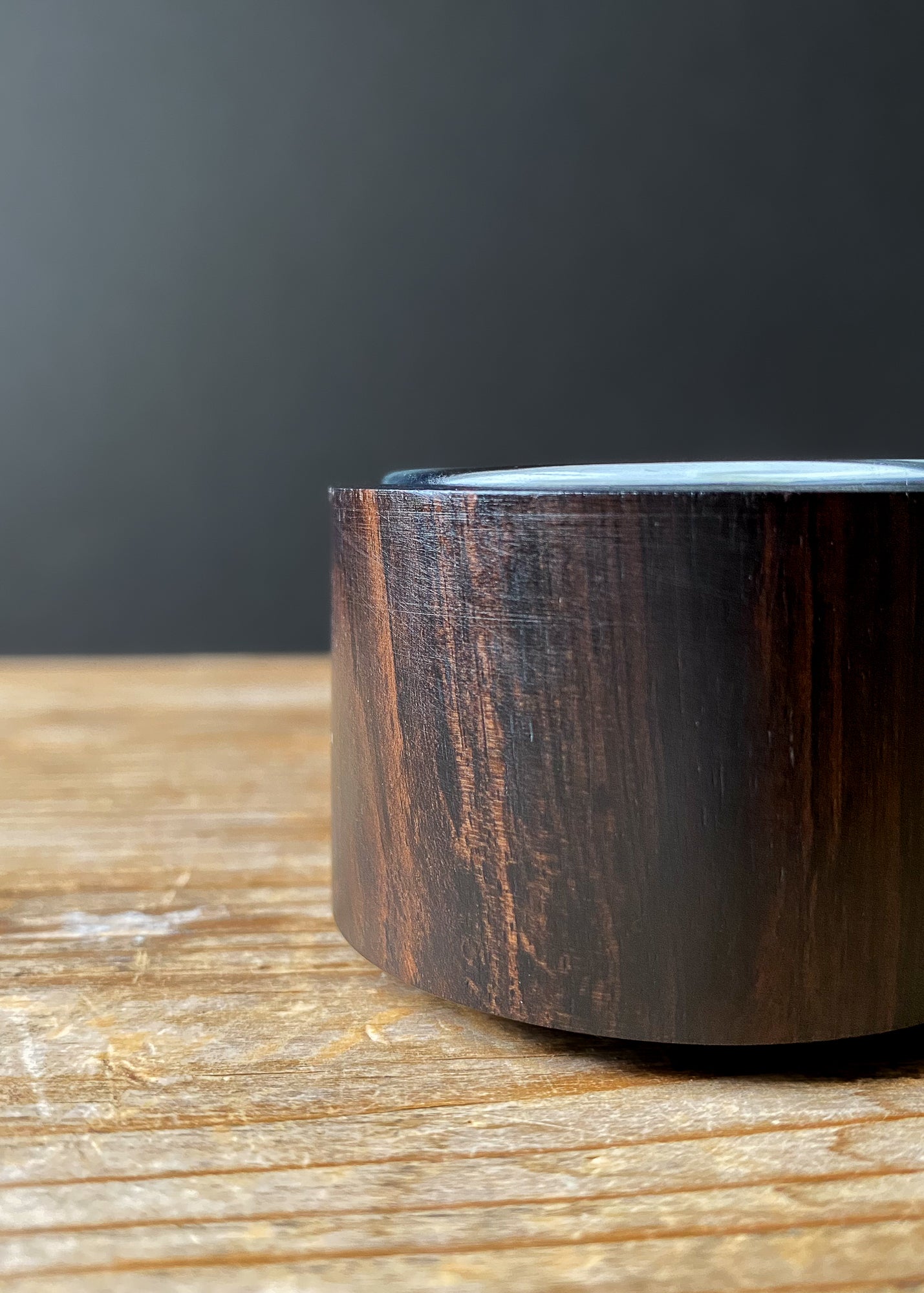 Detailed shot of a single dark wood candle holder, highlighting its smooth finish and rich natural wood grain, with a glass insert visible at the top.