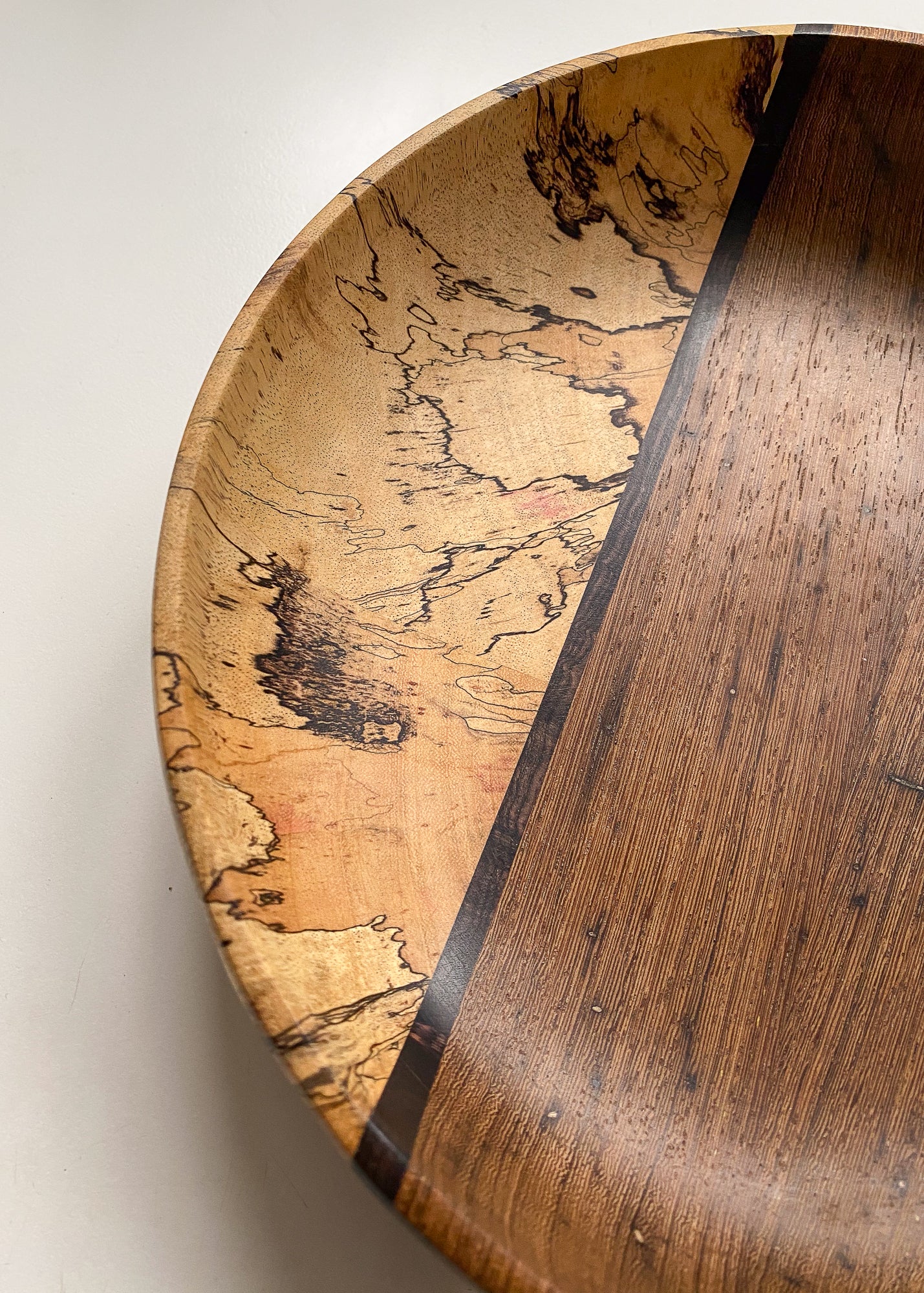 Close up view of segmented wooden bowl with spalted wood on white background.