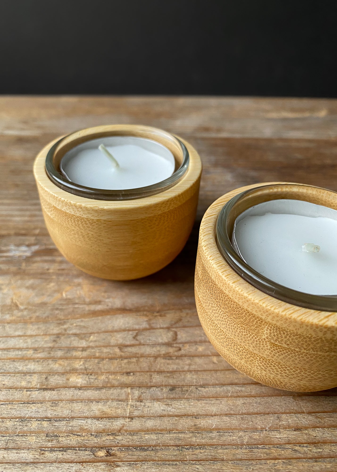 Pair of bamboo candle holders with clear glass cups and tea light candles.