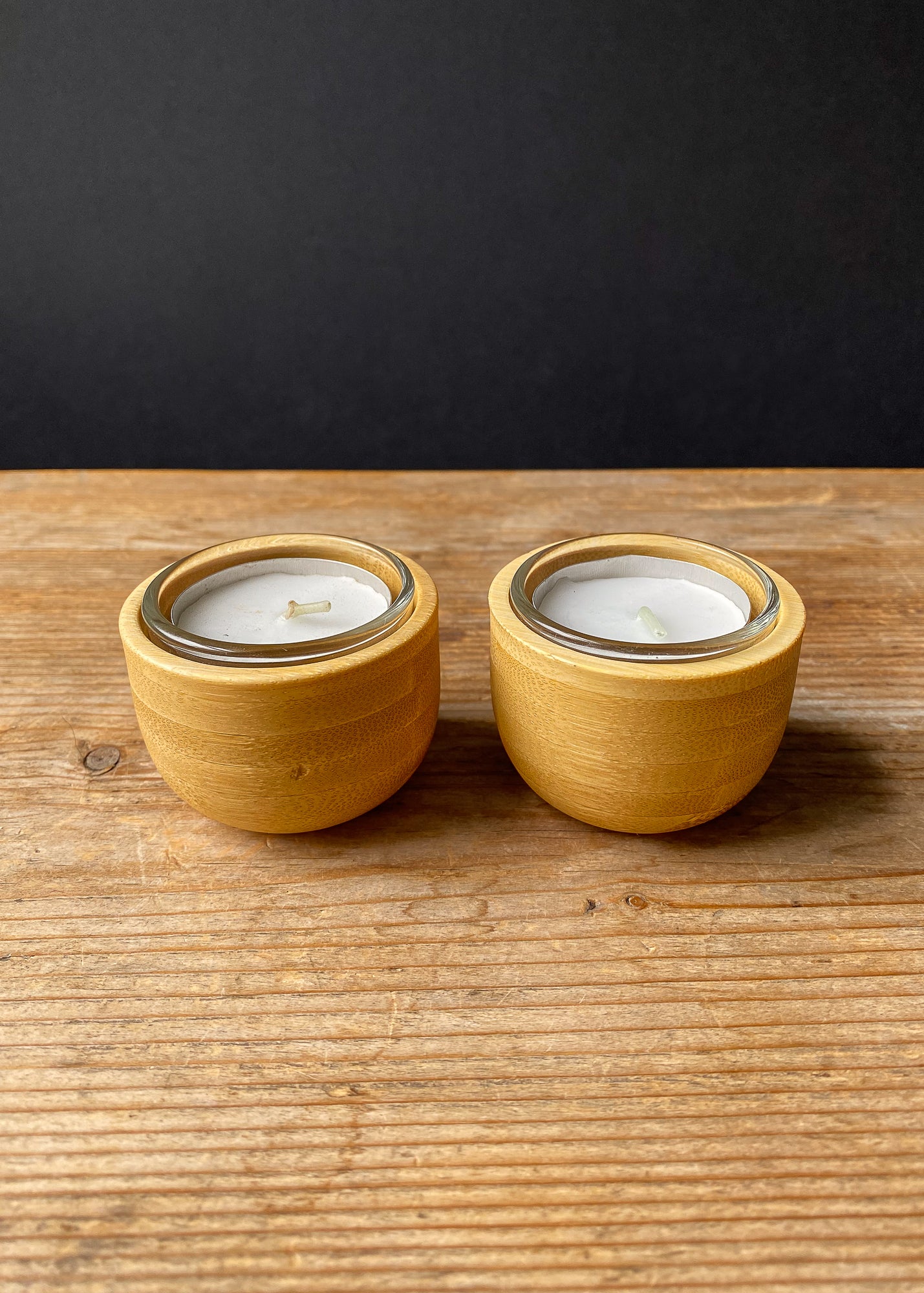 Pair of bamboo candle holders with clear glass cups and tea light candles.