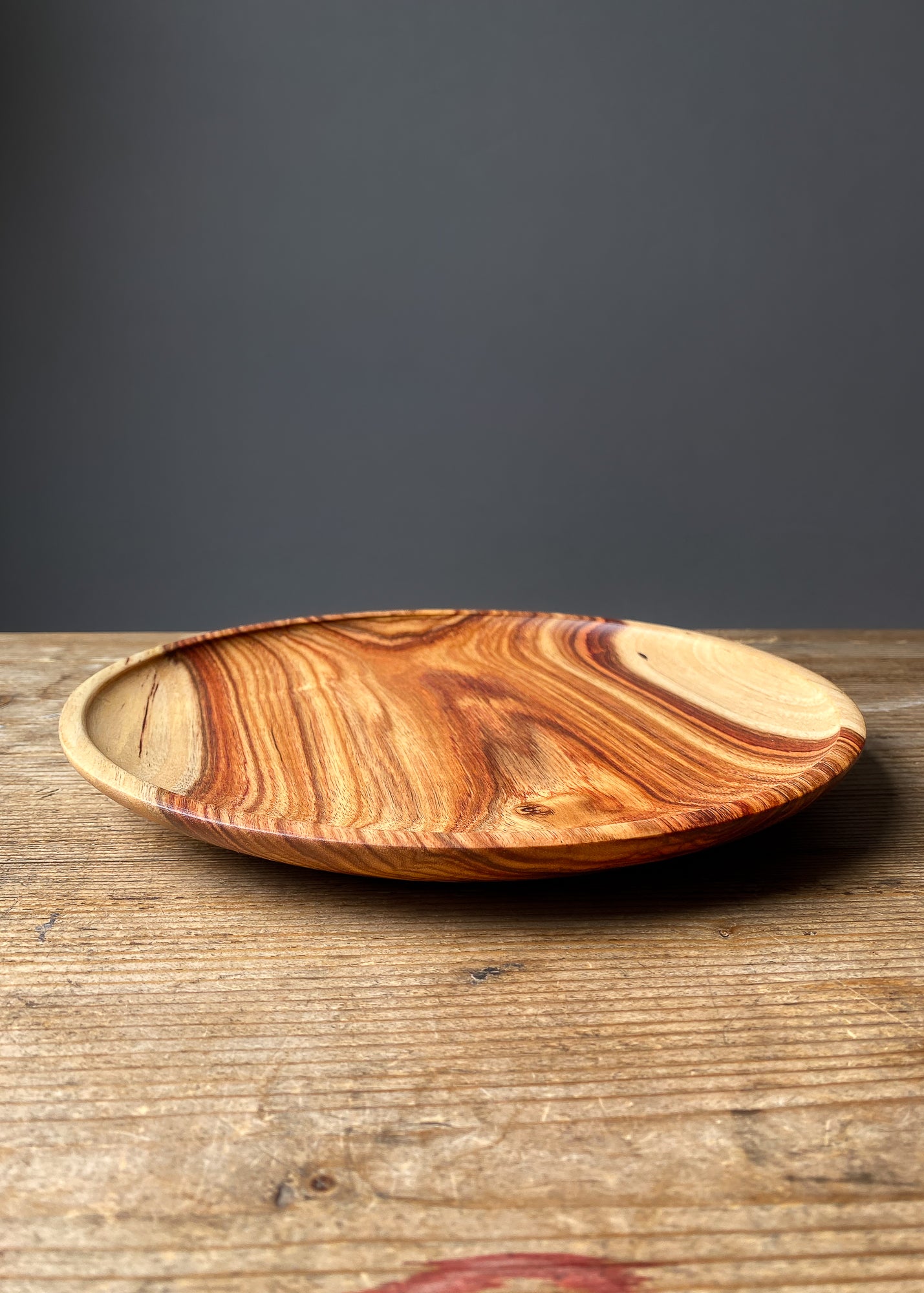 Large patterned orange wooden tray on wood table with black background.