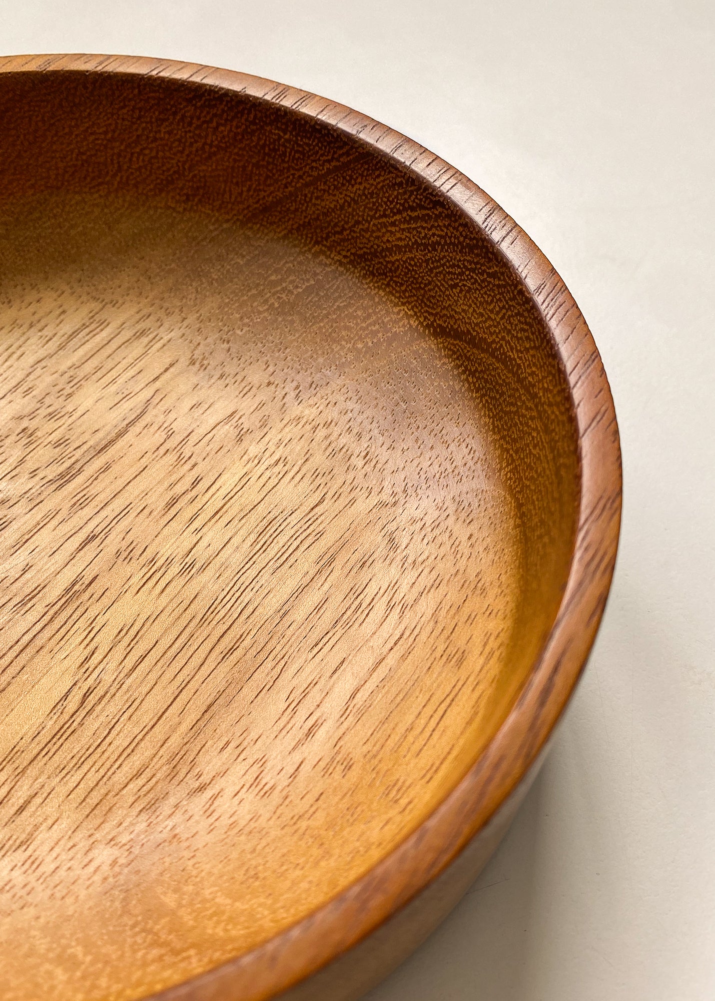 Close up view of Iroko wooden bowl on white background.