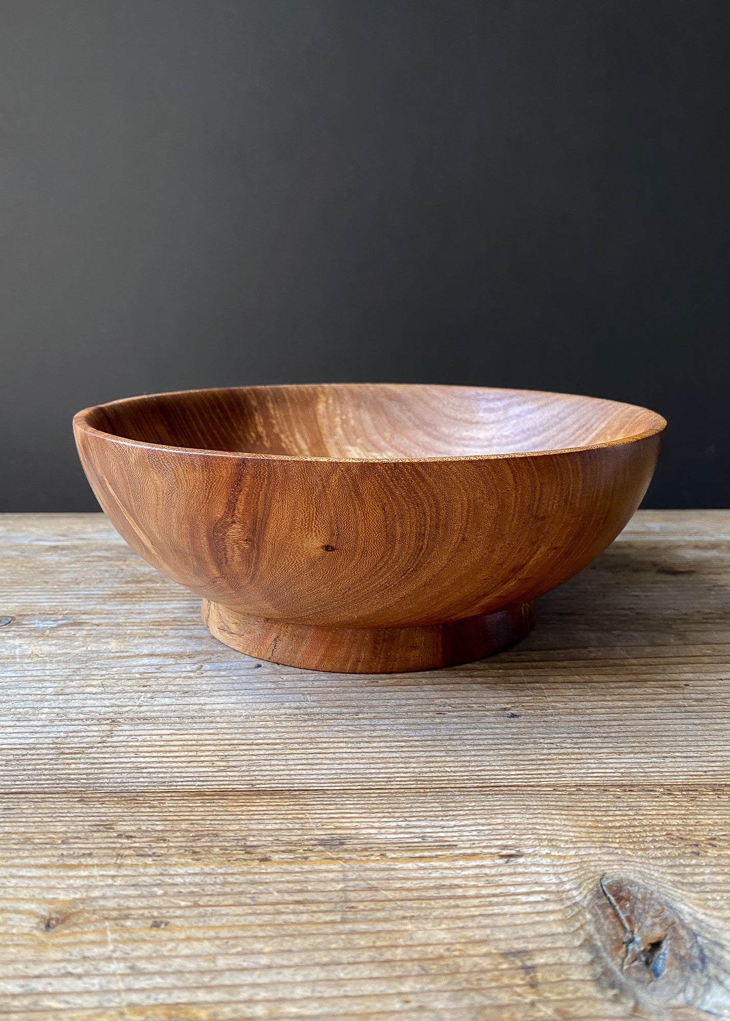 Elm wood fruit bowl on wooden table.