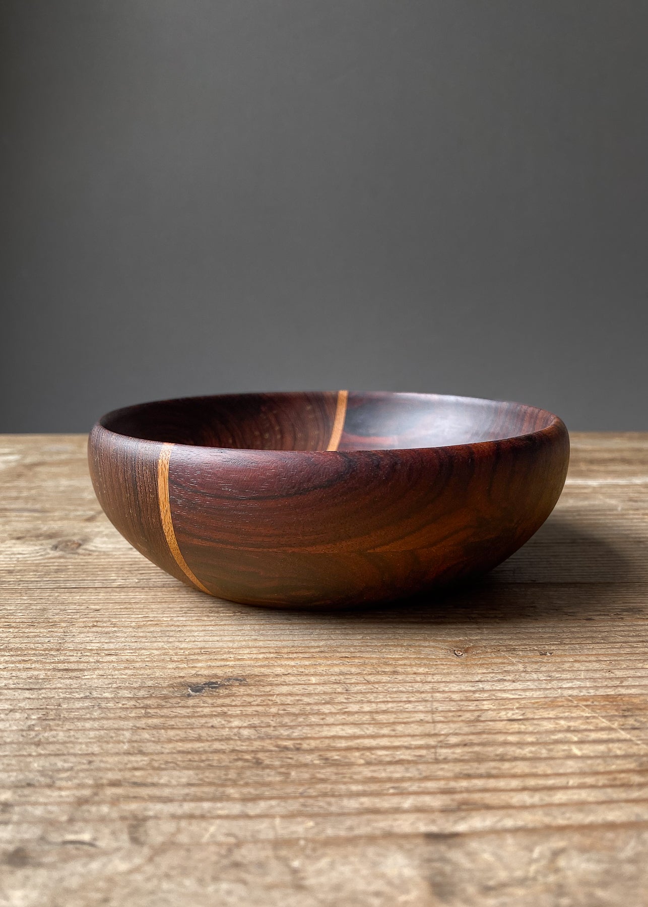 Dark segmented wooden bowl on wood table.