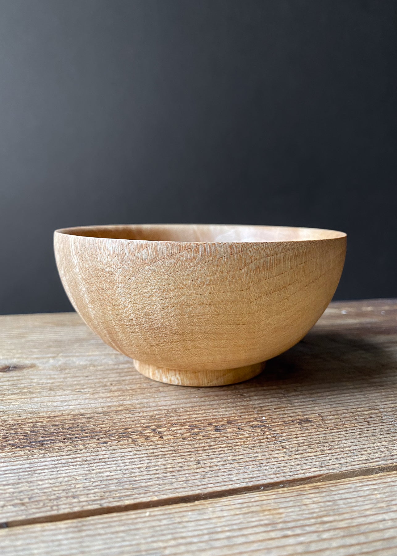 Small Sycamore wood bowl on wooden table.