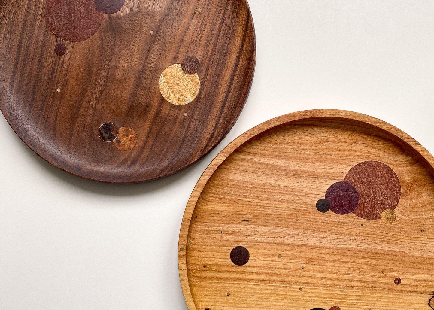 Two wooden trays with inlaid circular patterns on a white background