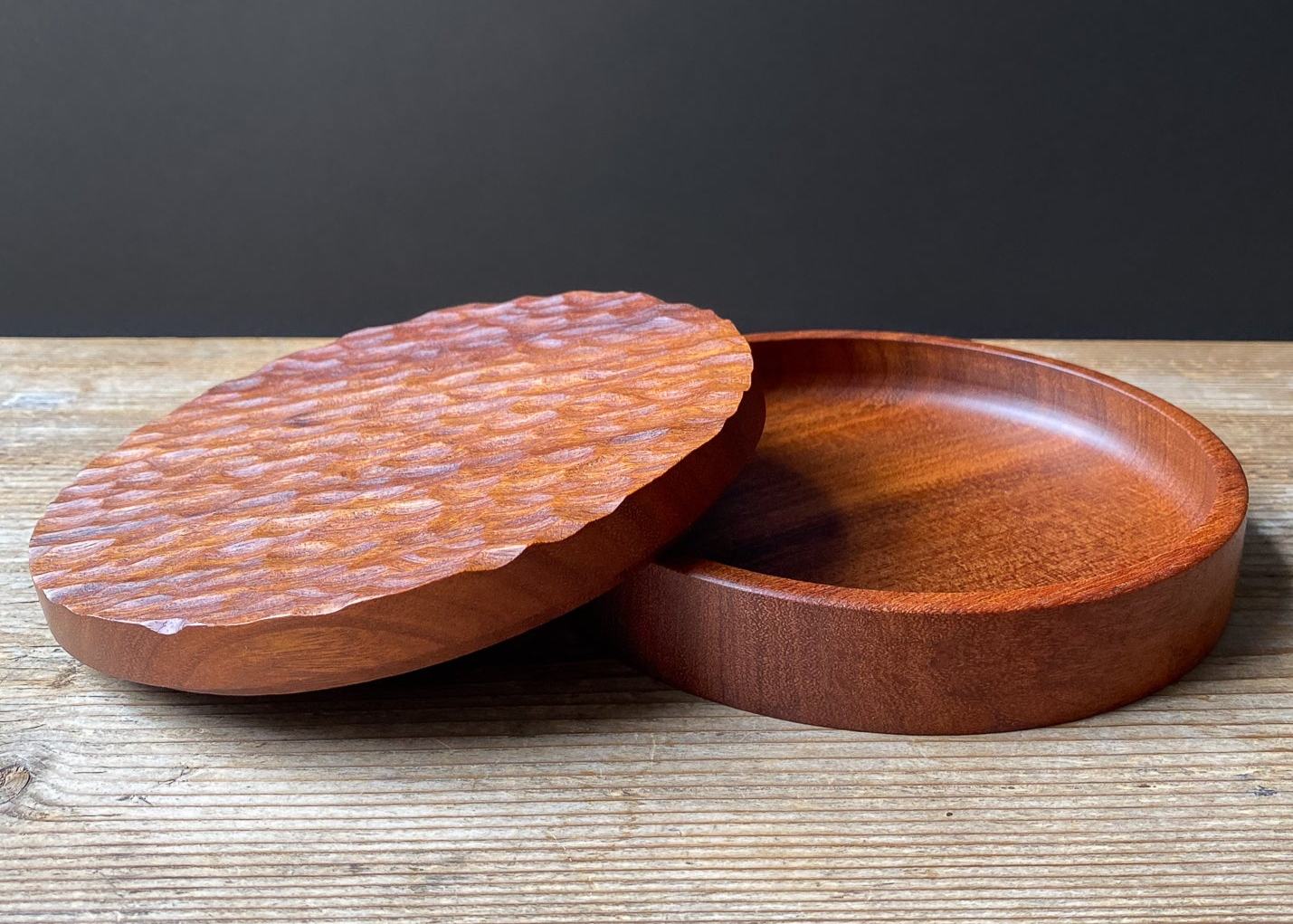 Wooden bowl and lid on a wooden surface with a dark background
