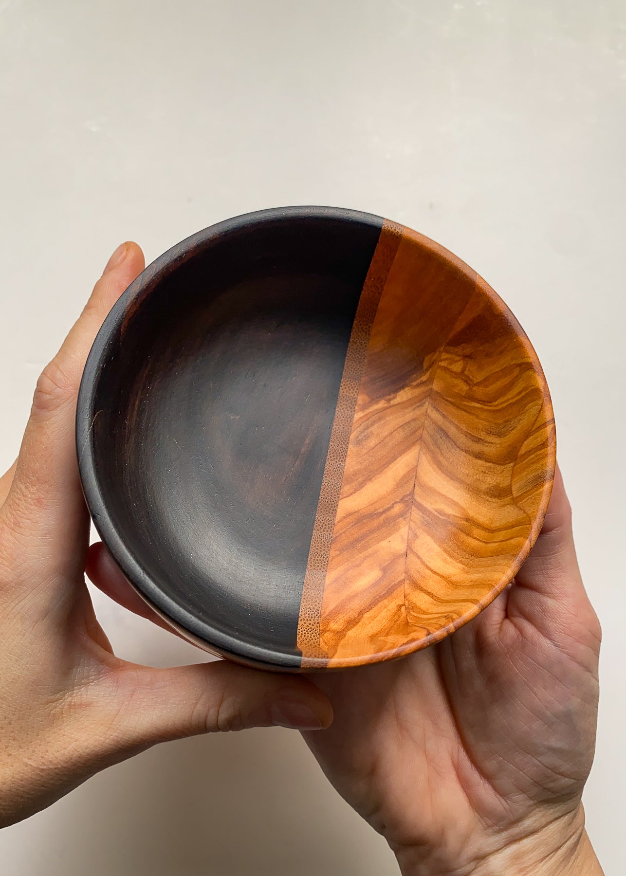 Segmented wooden bowl held in hands on white background.