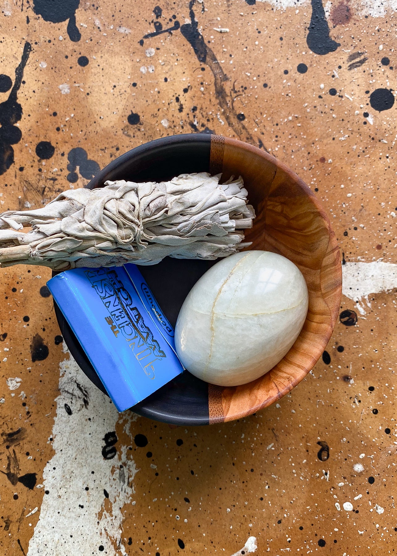 Top view of segmented wooden bowl with household items on textured background.