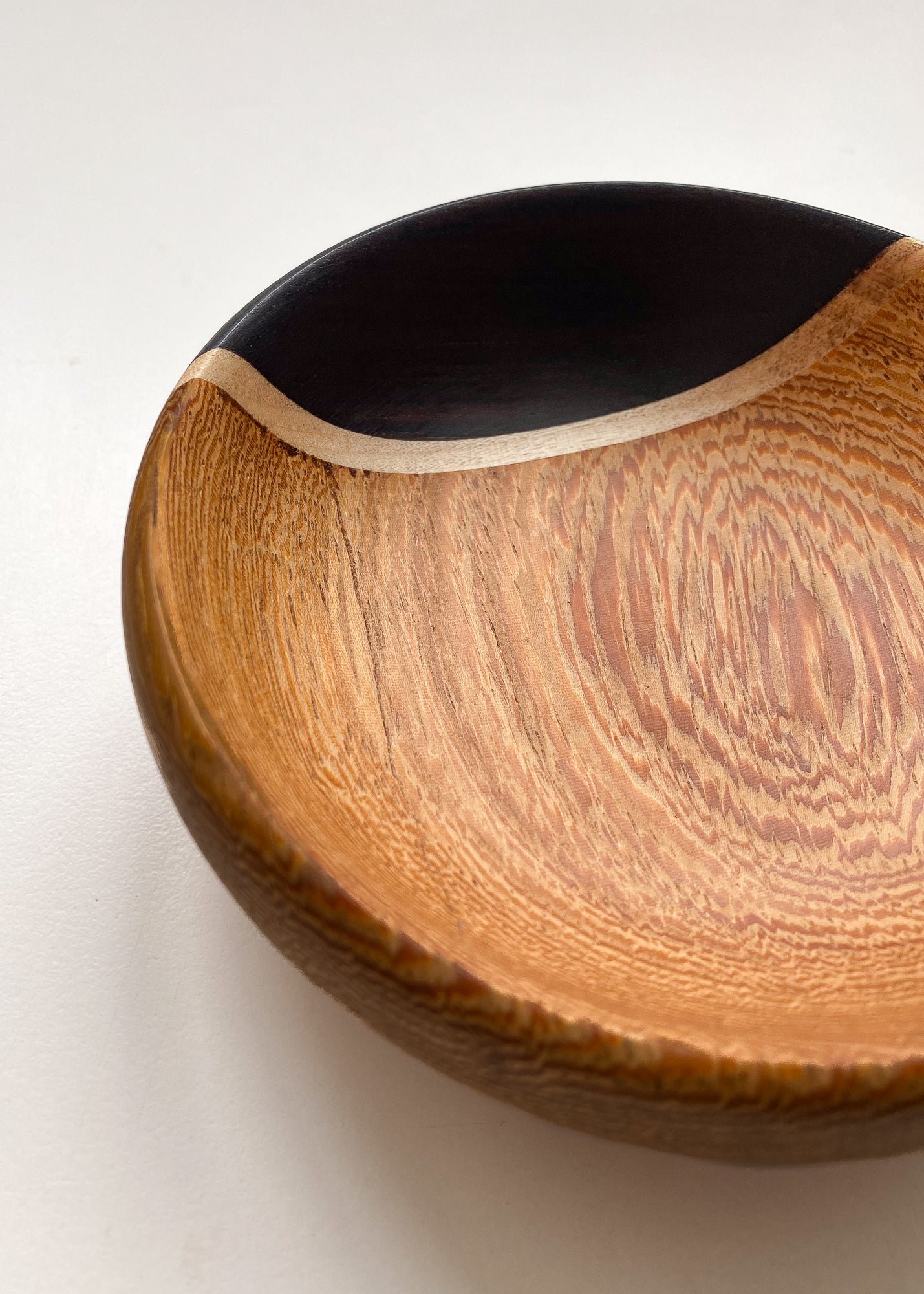 Close up view of inside segmented black and orange wooden bowl on white background.
