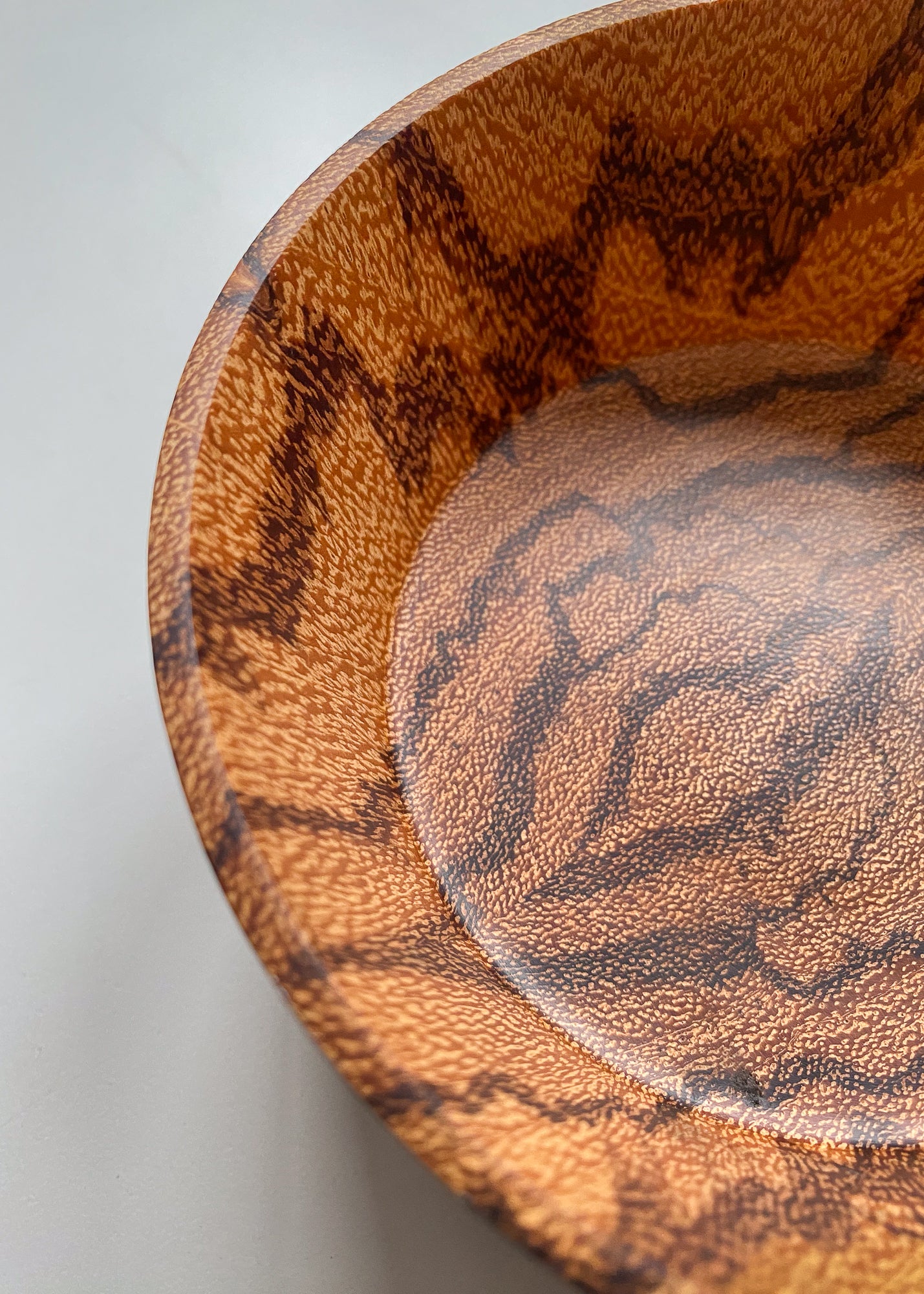 Inside close-up patterned orange Marblewood wooden bowl on white background.