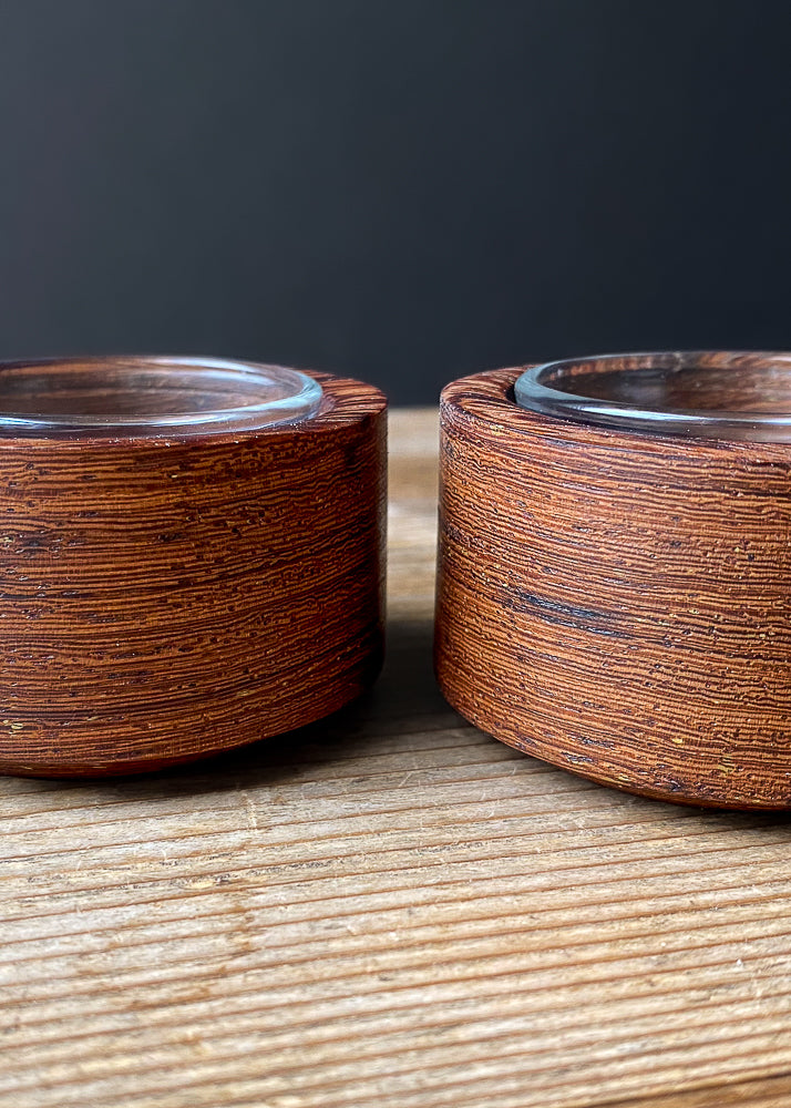 Detailed view of two Panga Panga candle holders with glass inserts on wooden table.