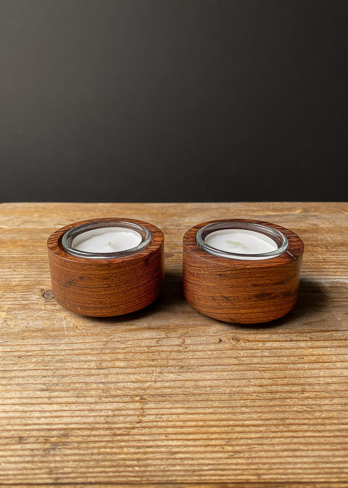 Two Panga Panga wood candle holders with tea light candles against dark background.