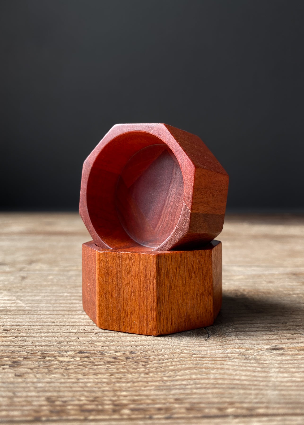 Two stacked pink octagonal wooden bowls on wood table.