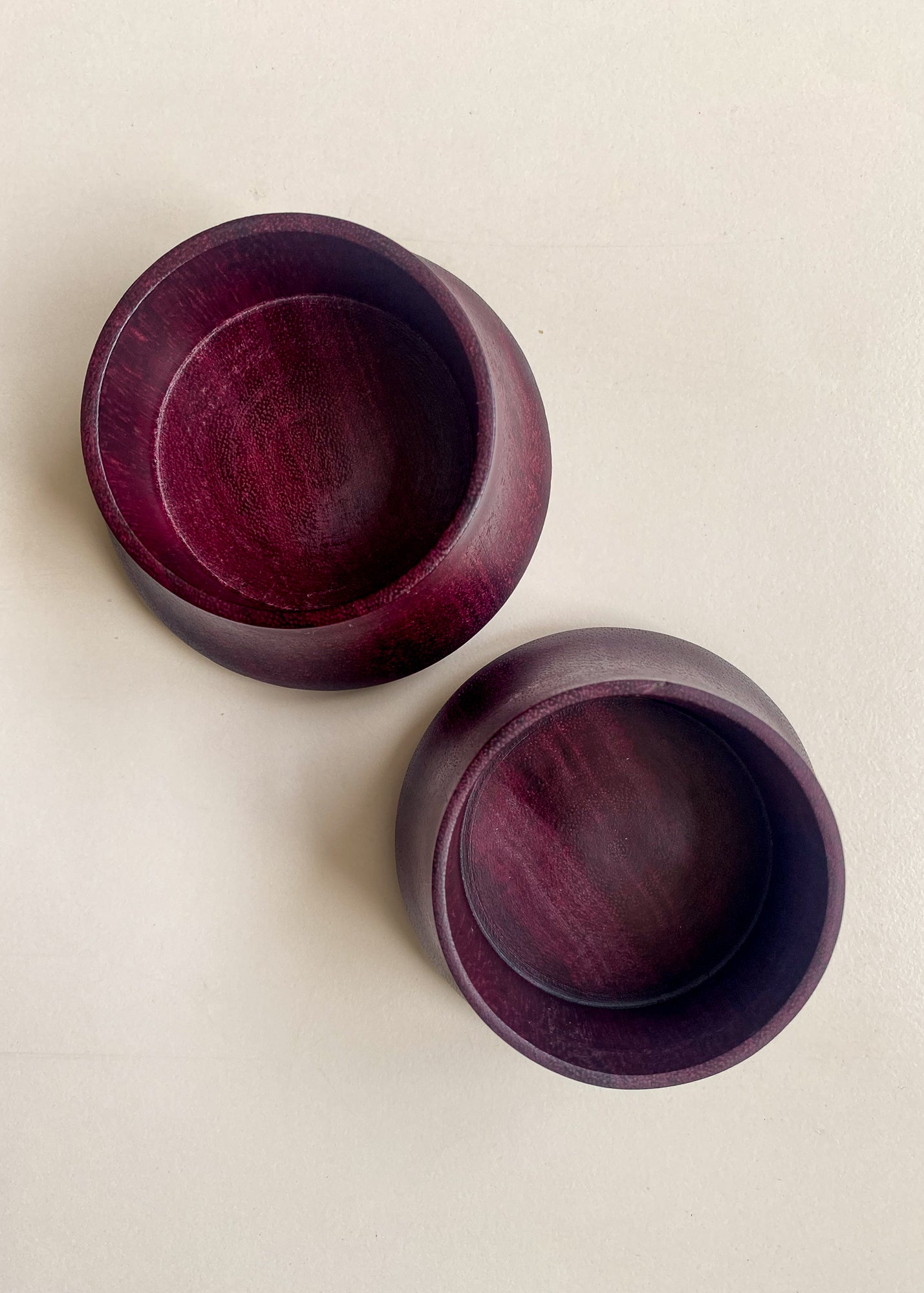 Overhead view of two Purpleheart wooden candle holders on white background.