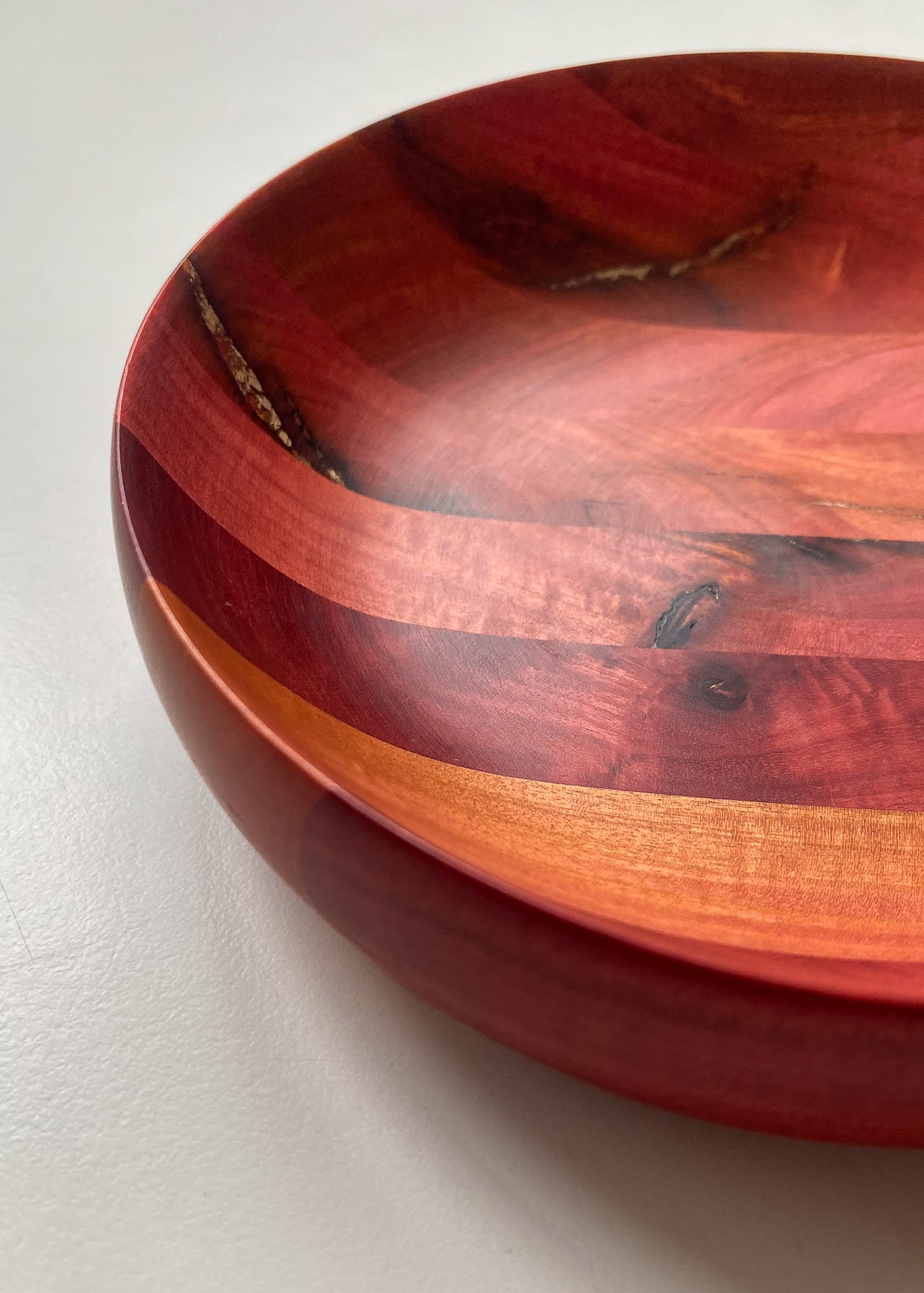 Close up inside view of segmented pink wooden bowl with bronze inlay on white background.
