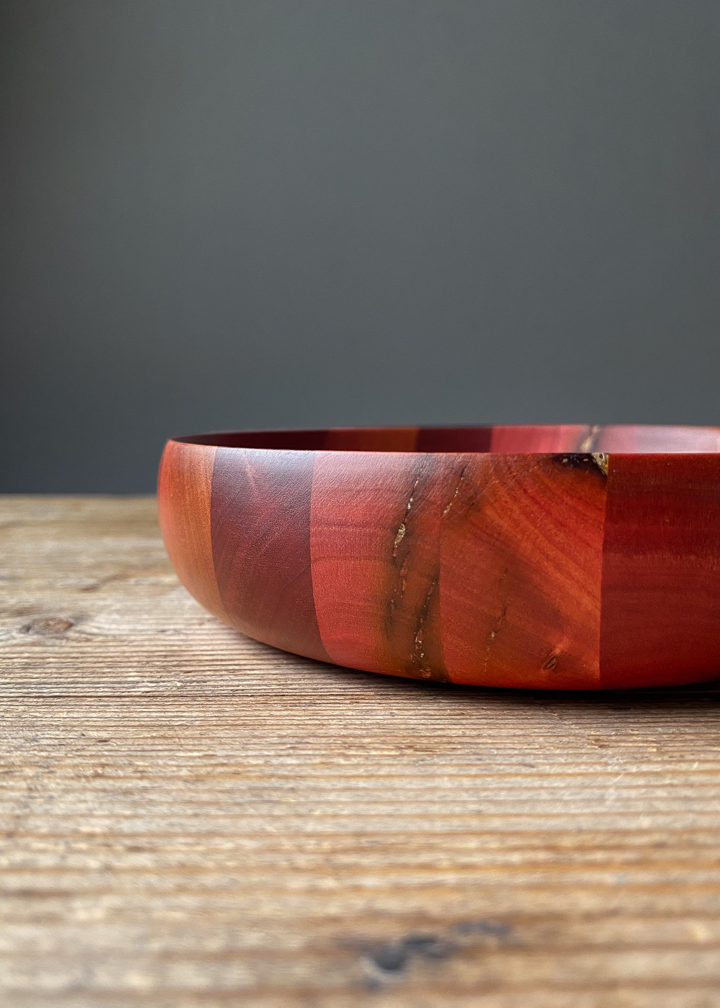 Close up side view of segmented Pink Ivory wooden bowl on wood table.