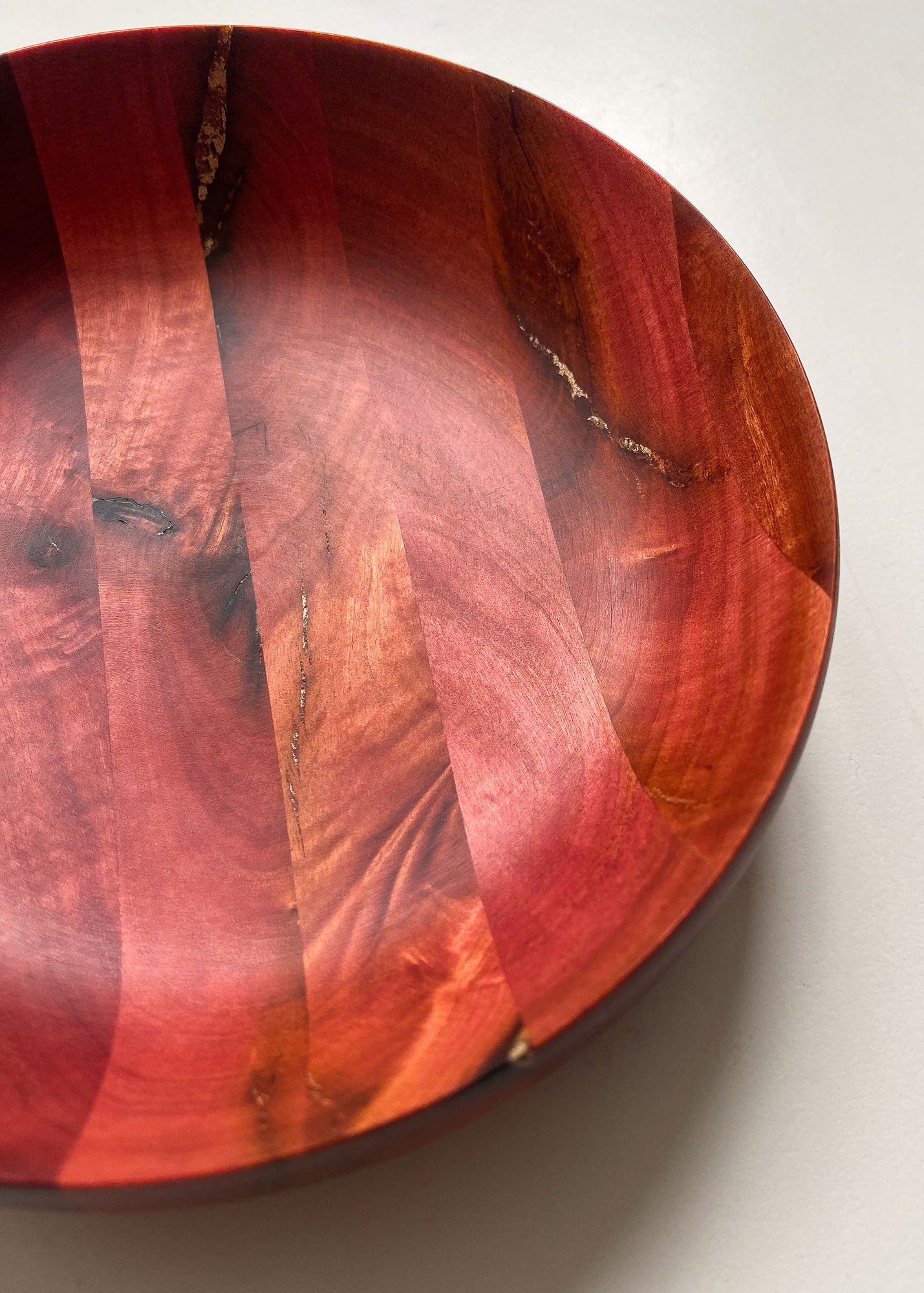 Close up inside view of segmented Pink Ivory wooden bowl with bronze inlay on white background.