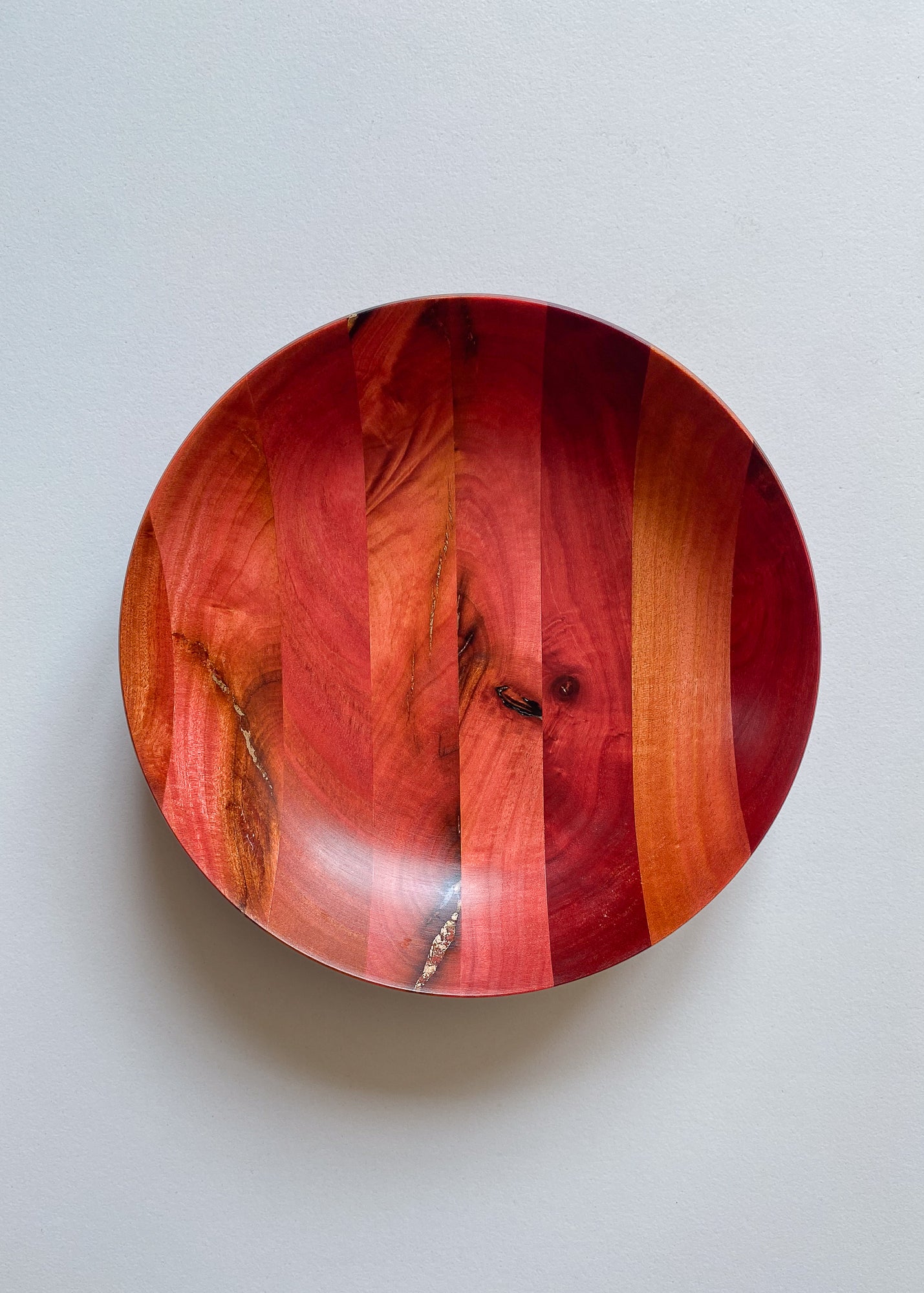 Overhead view of segmented Pink Ivory and bronze wooden bowl on white background.