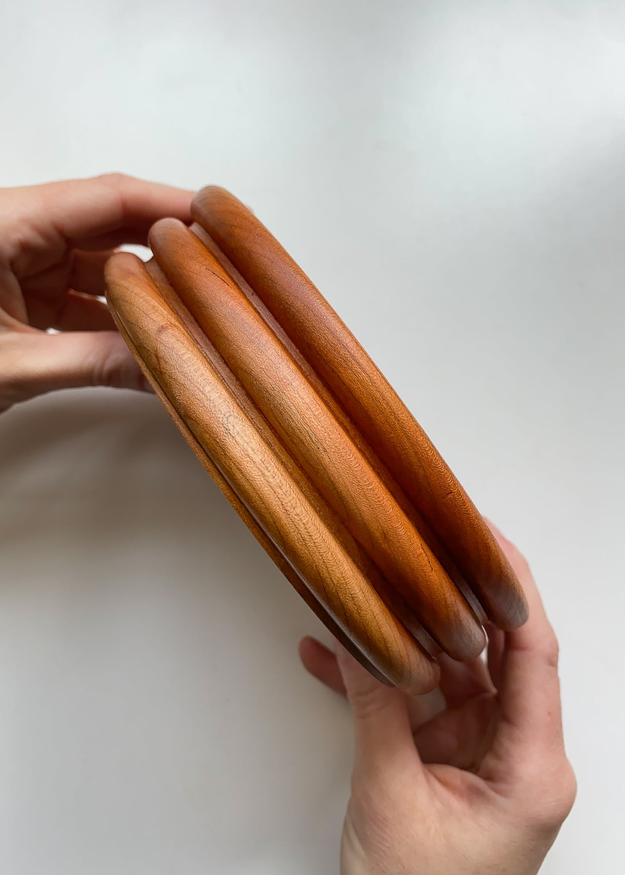 Side view of Cherry wood bowl held in hands on white background.