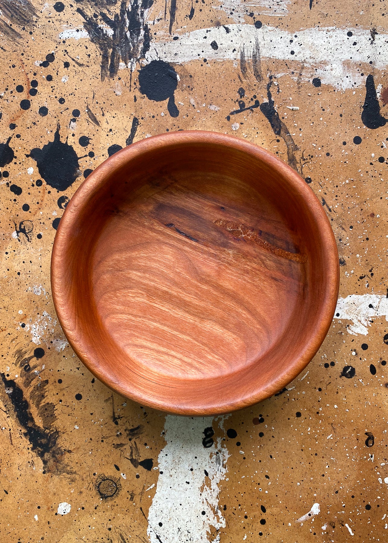 Overhead view of orange wooden bowl on textured background.