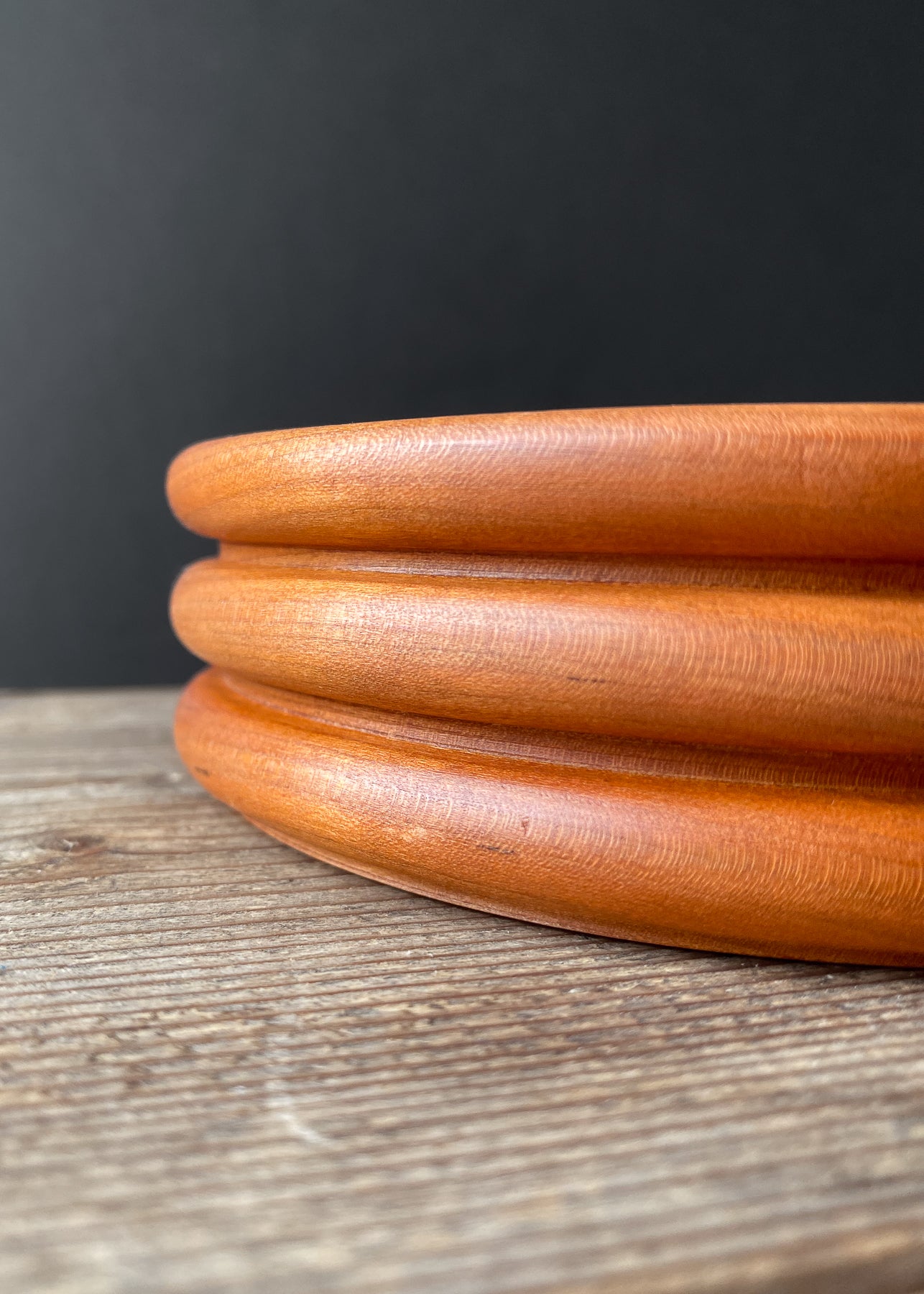 Close up side view of orange Cherry wood bowl on wooden table.