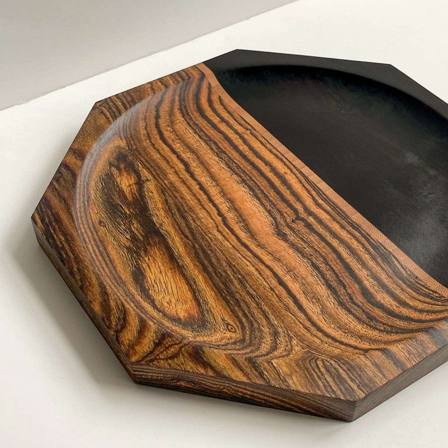 Close up overhead view of octagon shaped segmented wooden plate against white background.