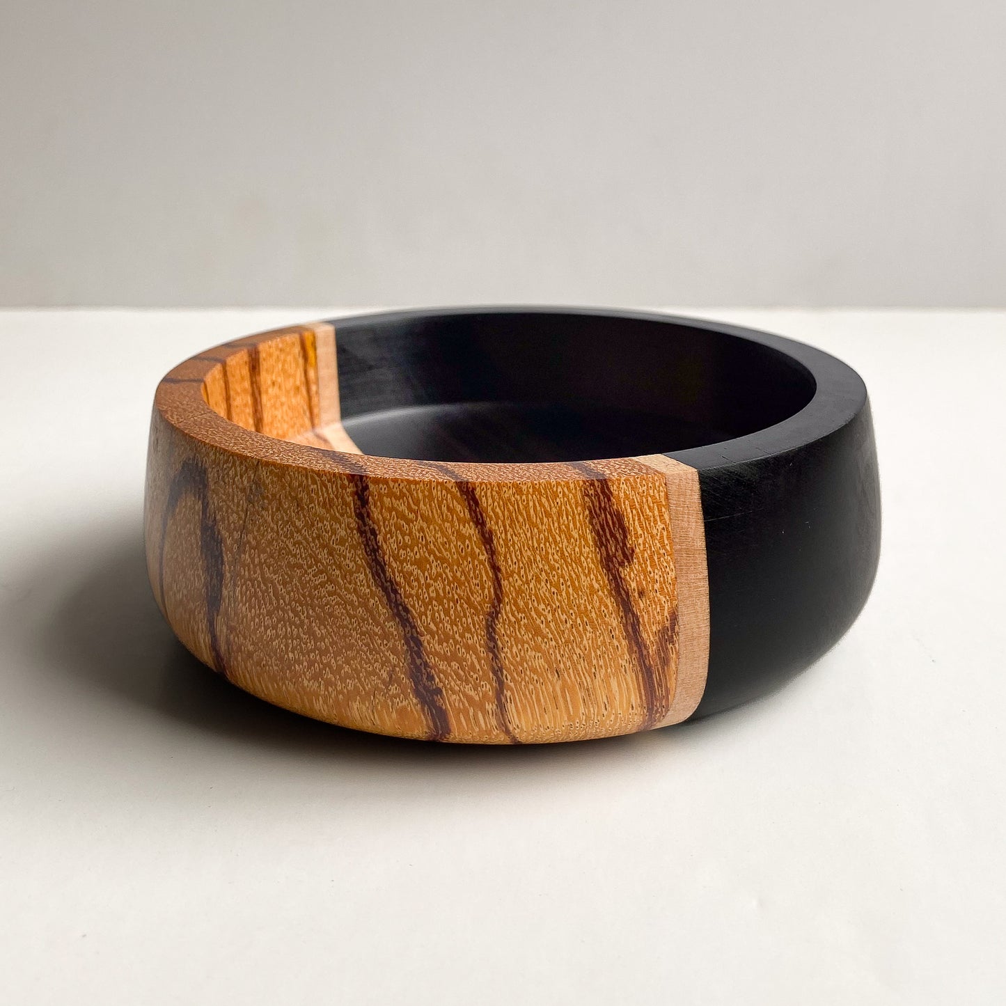 Segmented orange and black wooden bowl against white background.