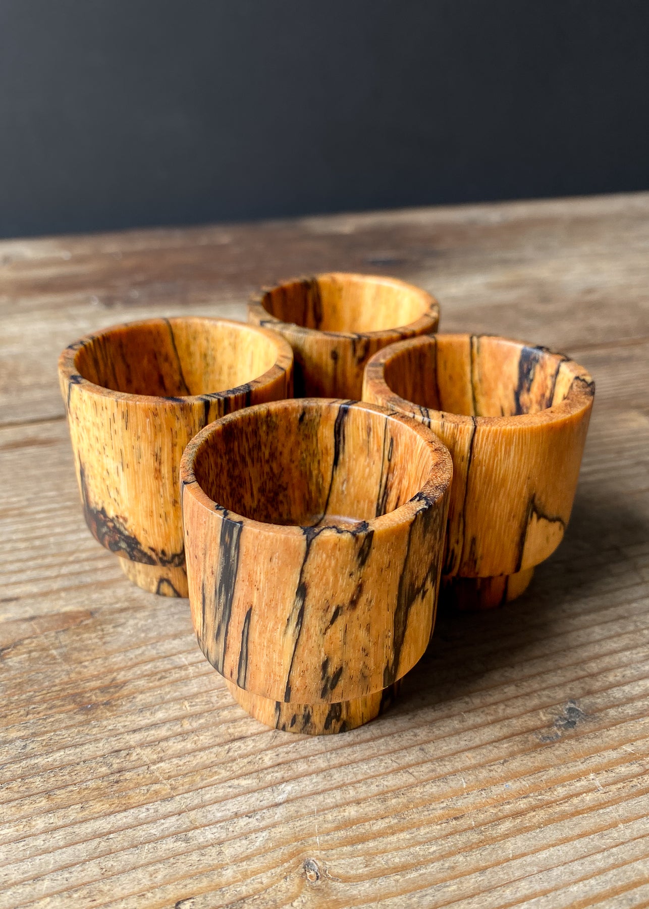 Four small wooden bowls on wood table.