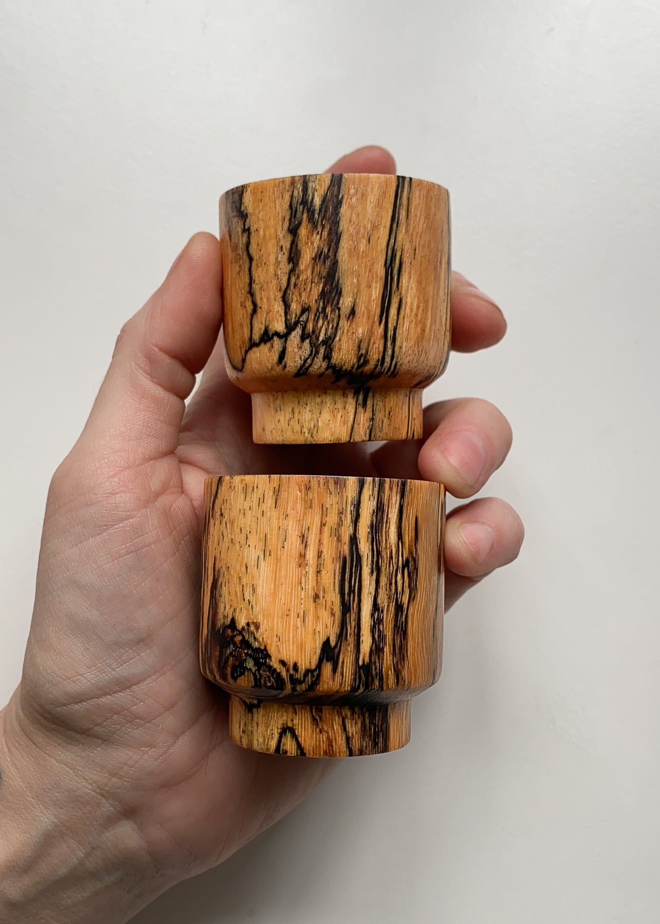 Two small wooden bowls held in hand on white background.