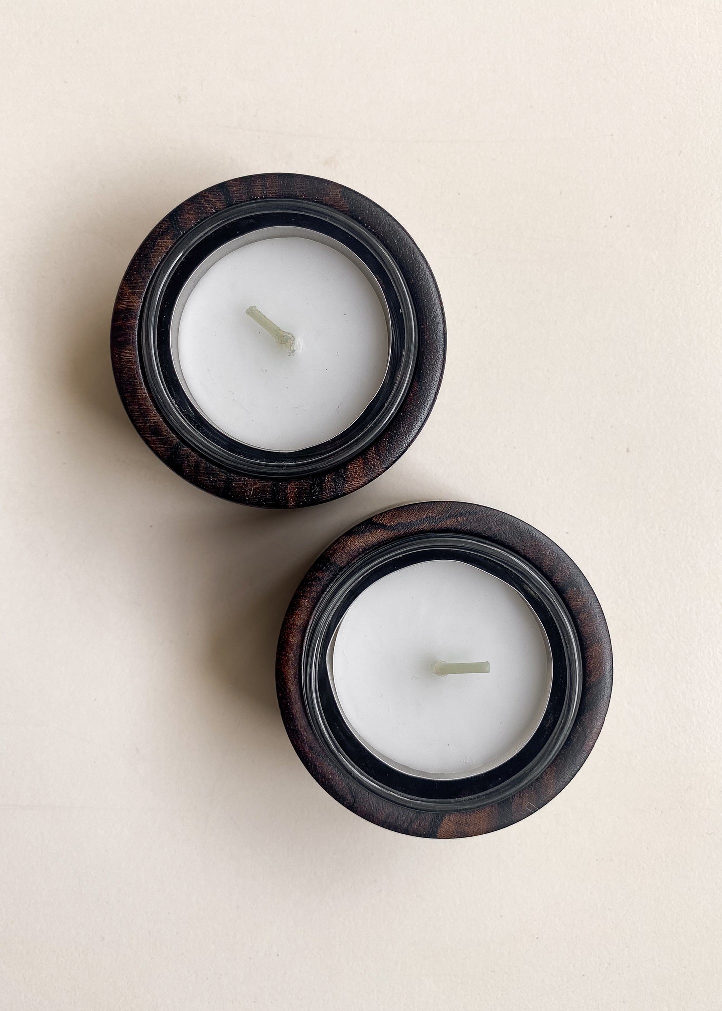 Overhead view of two Ziricote candle holders with tea lights against white background.