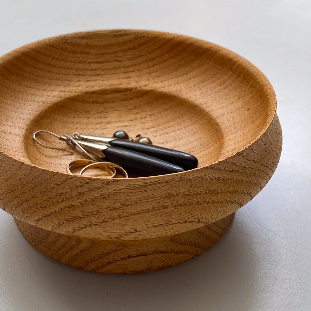 Wooden bowl with jewelry on a white background