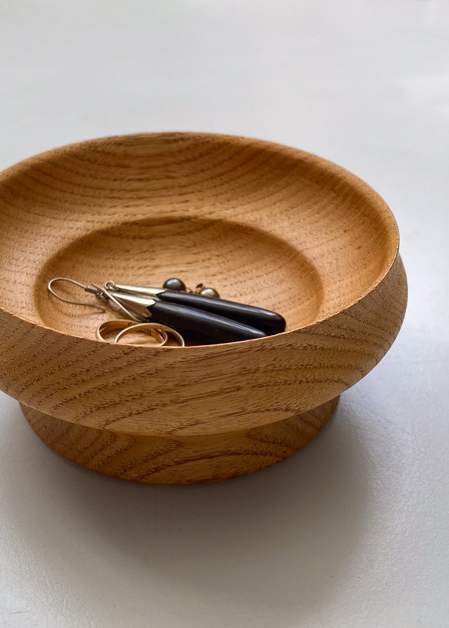 Wooden bowl with jewelry on a white background