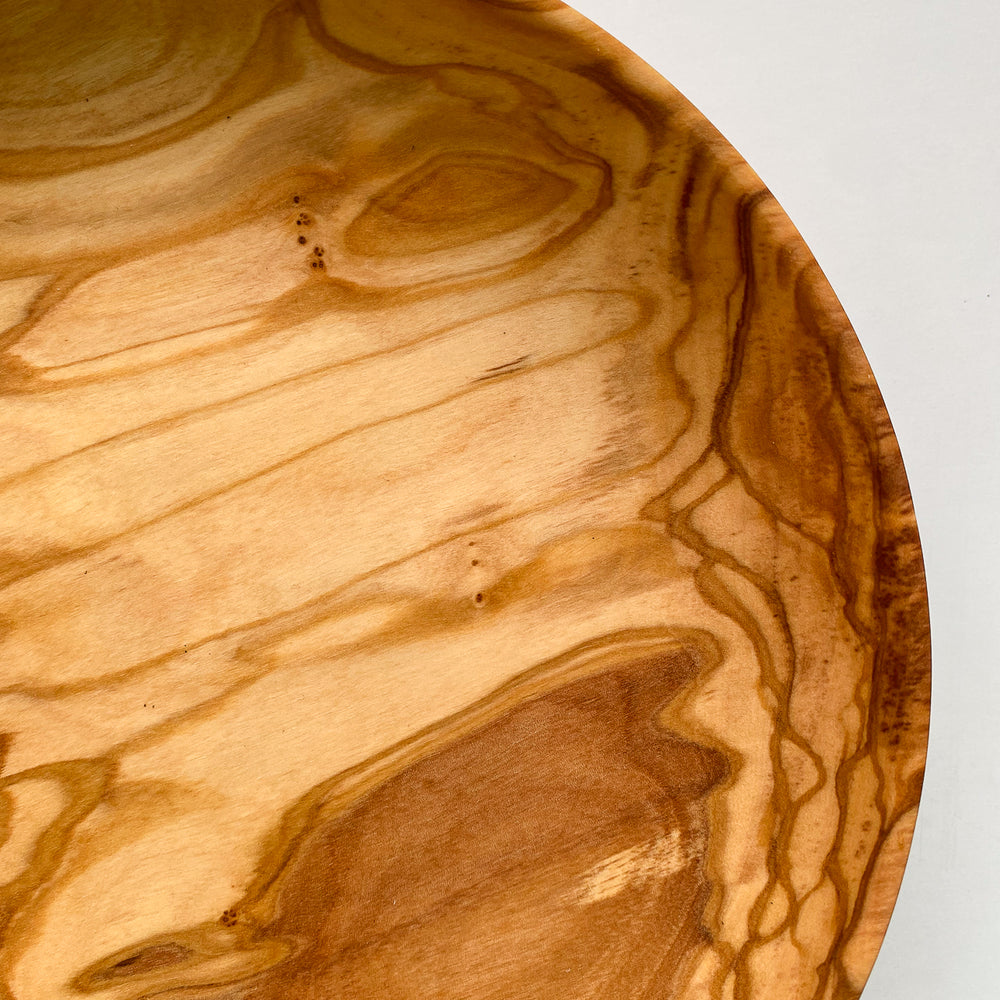 Close up overhead view of olive wood bowl on white background.