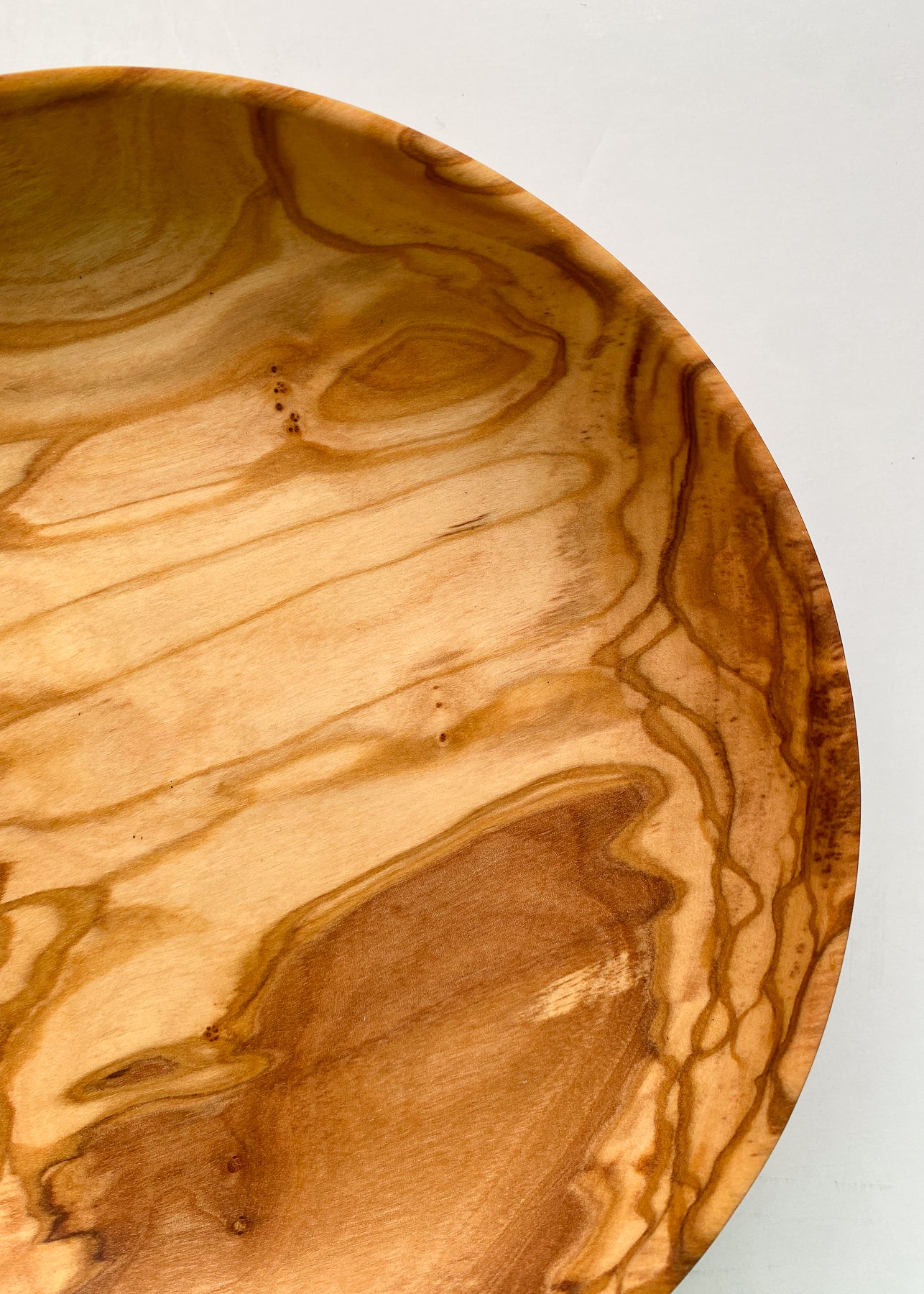 Close up overhead view of olive wood bowl on white background.