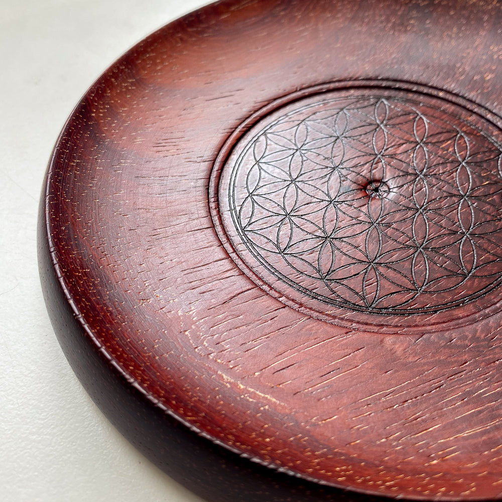 Red wooden incense holder with Flower of Life pattern against white background.