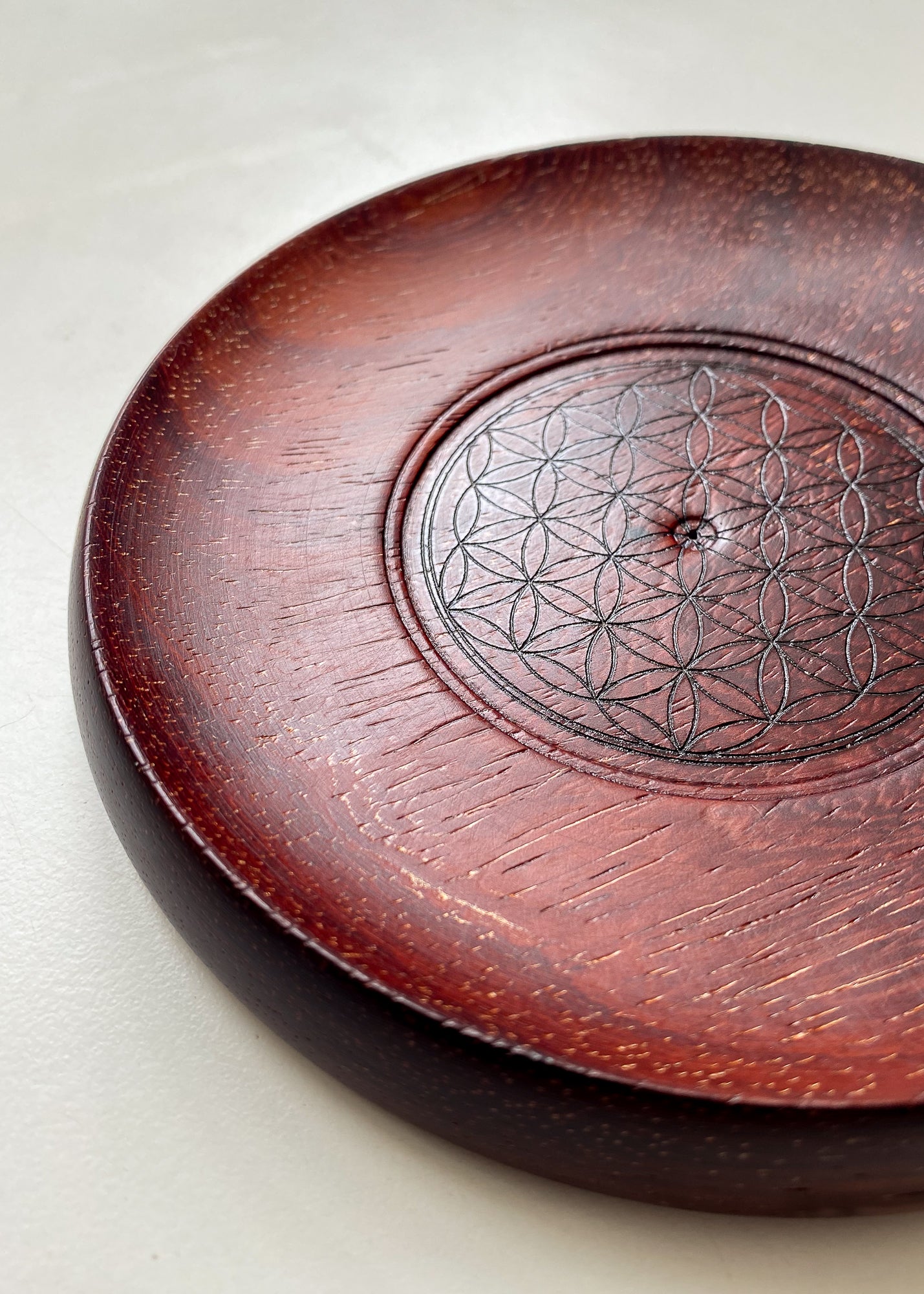 Red wooden incense holder with Flower of Life pattern against white background.