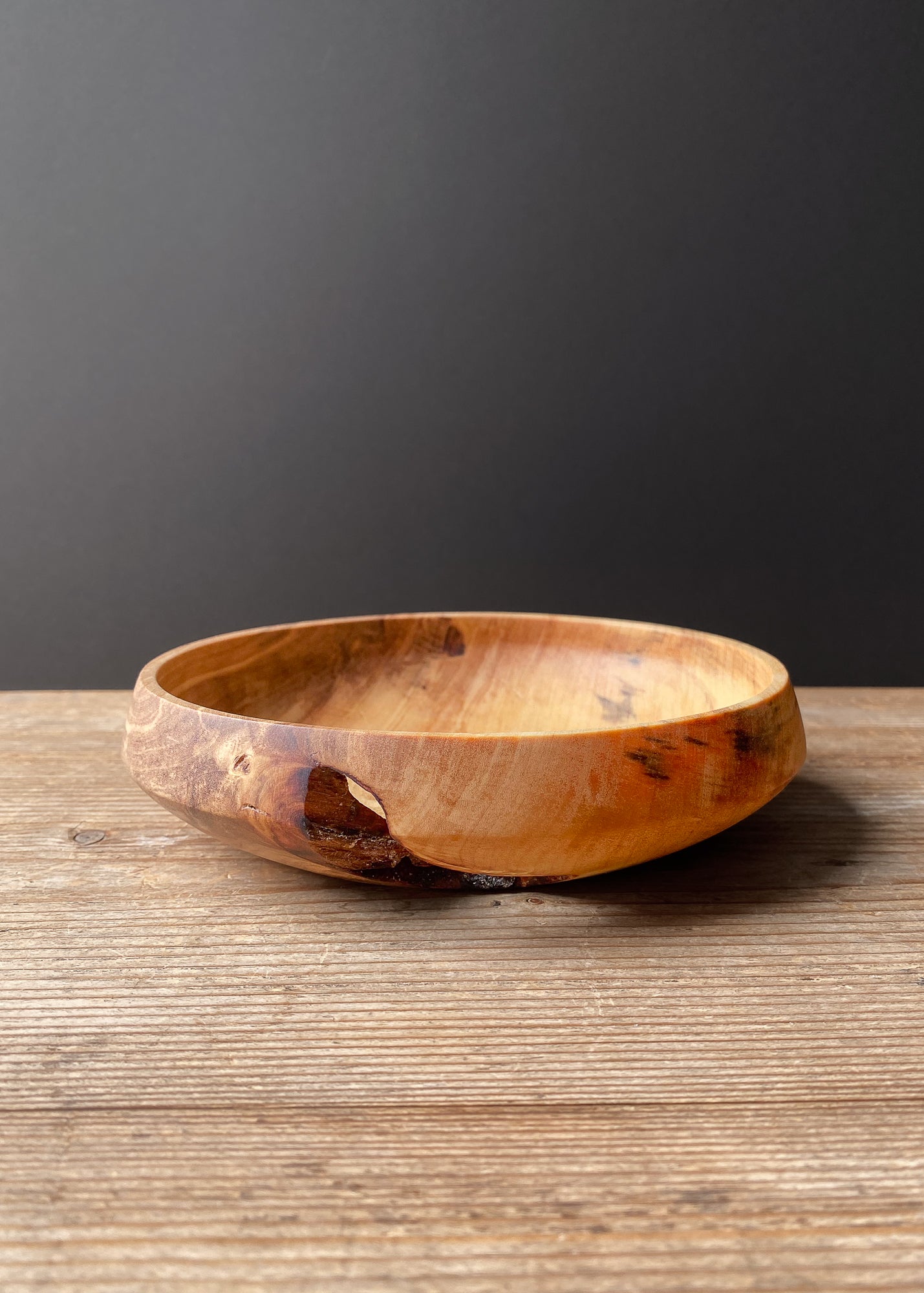 Live edge Tulip wood bowl on wooden surface with black background.