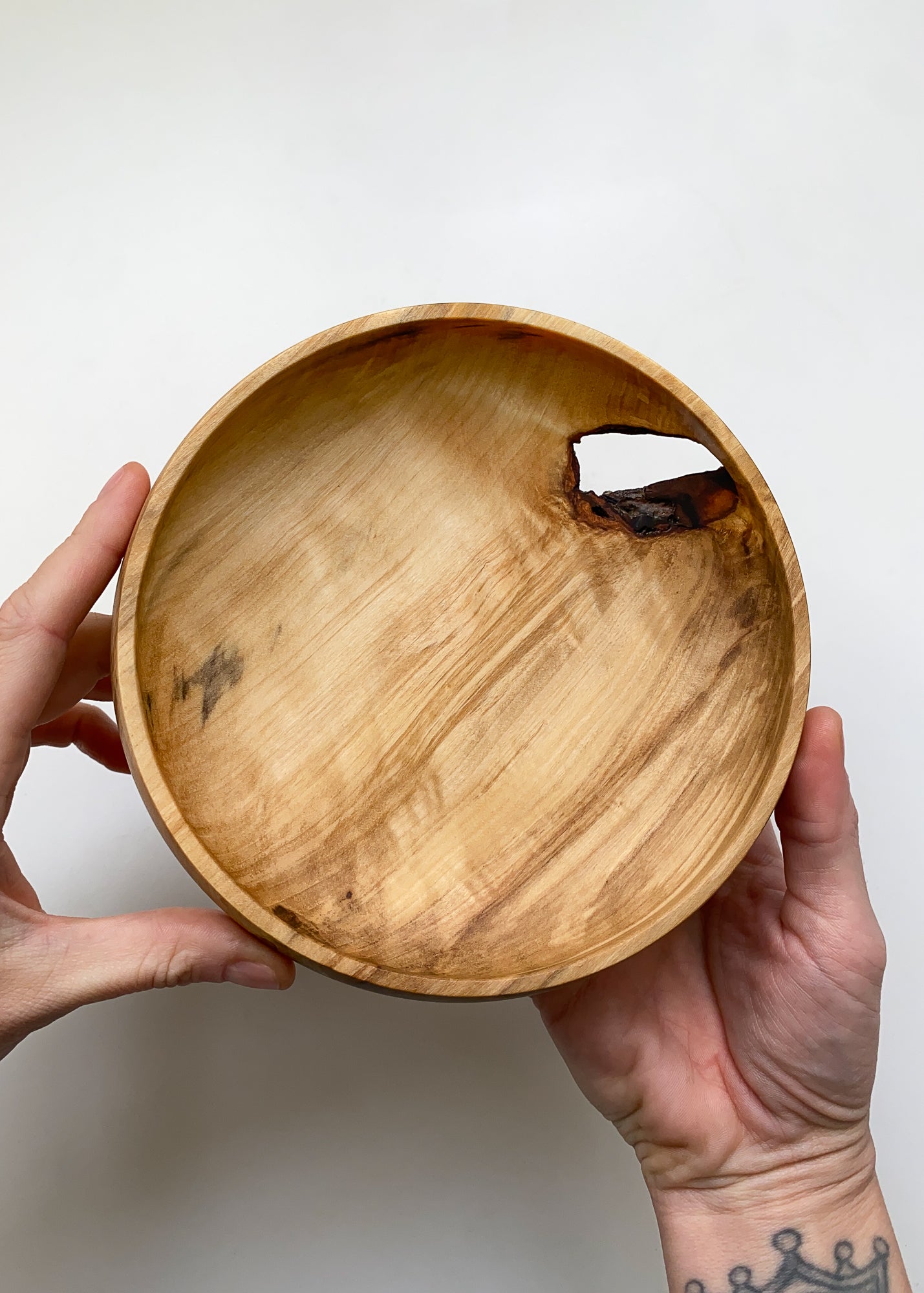 Live edge tulip wood bowl held by hands against a white background