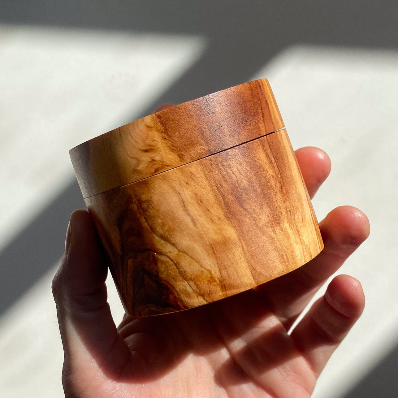 Olive wood jewely box held in hand in natural light against white background.
