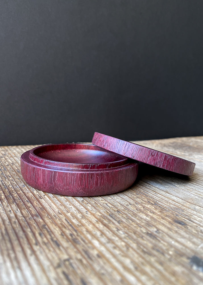 Detailed view of shallow purple wooden box with opened lid against dark background.