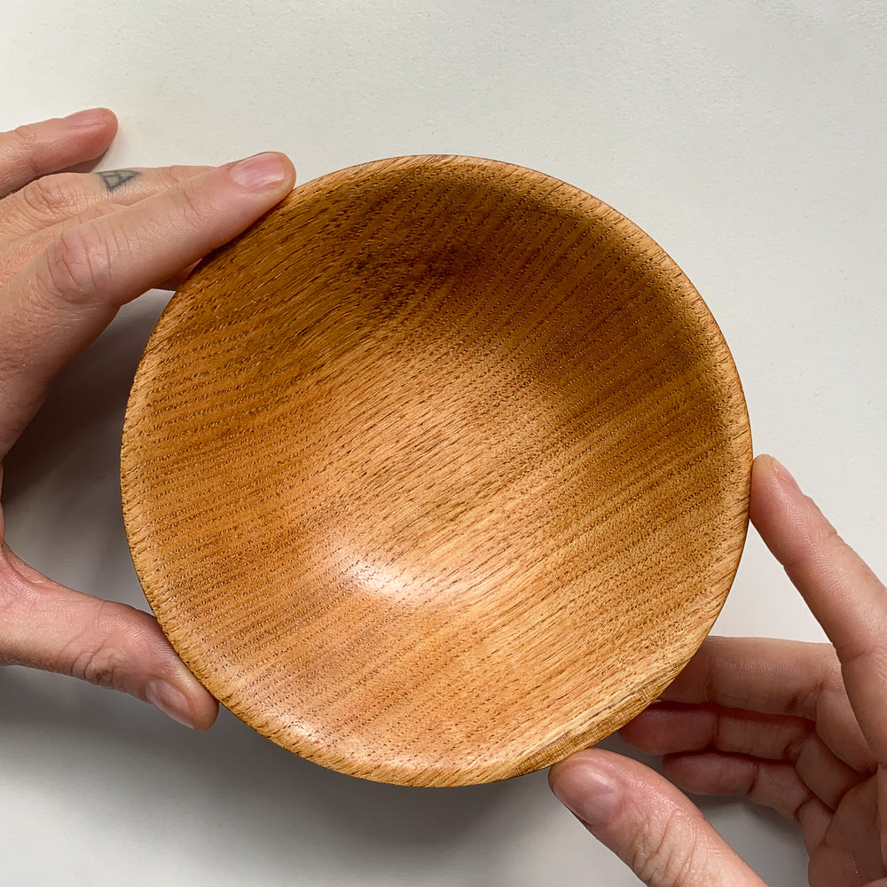 Overhead view of wooden bowl held by two hands against a plain background