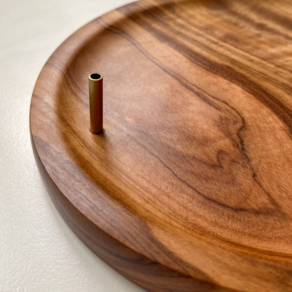 Close up of Olive wood incense holder with brass tube against white background.