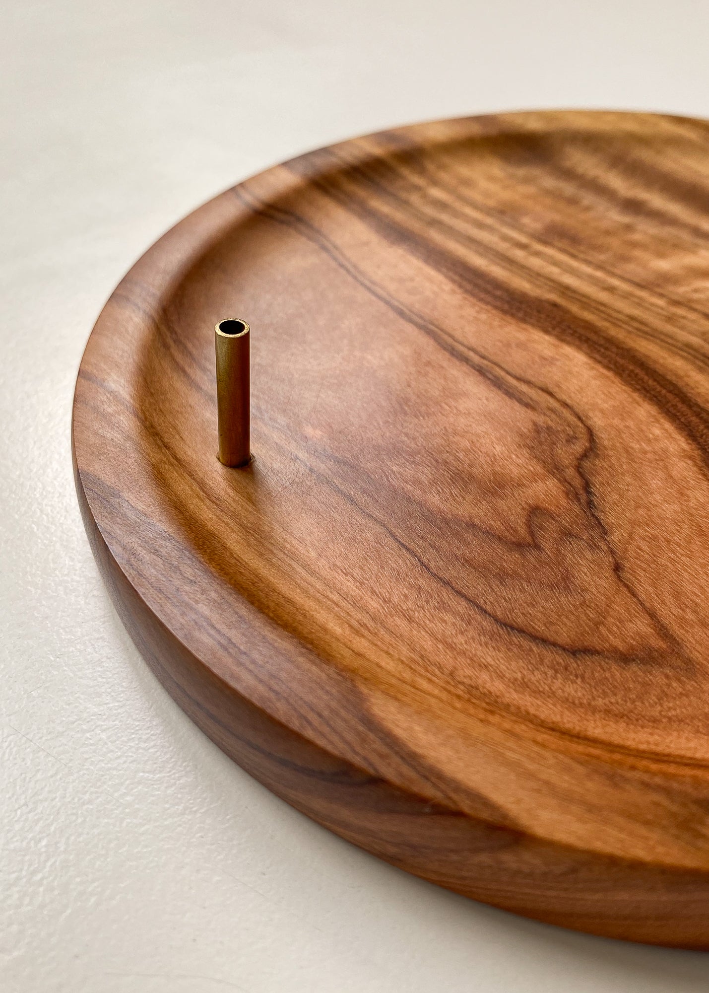 Close up of Olive wood incense holder with brass tube against white background.