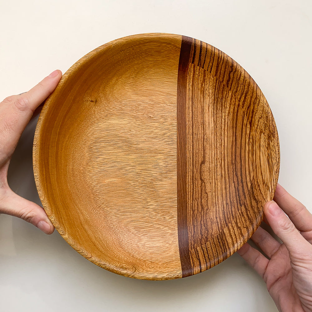 Segmented wooden bowl held in hands on a light background.