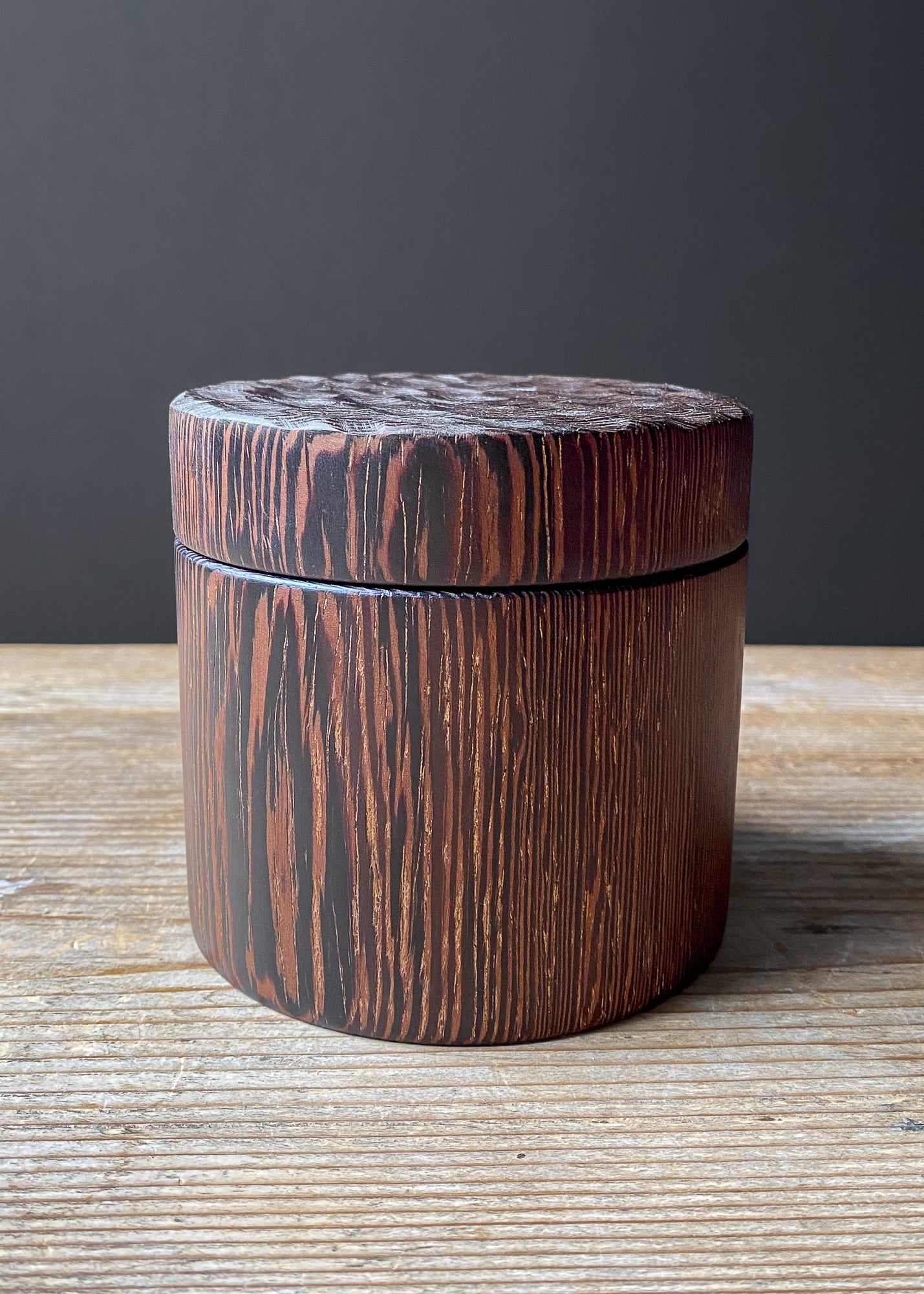 Wooden box with textured lid on a wooden surface against a dark background