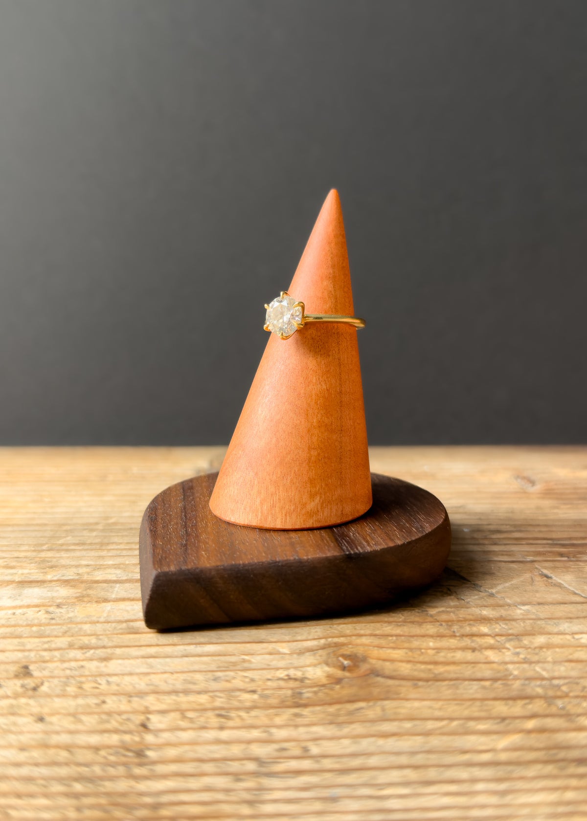 Ring on a wooden cone-shaped stand against a dark background
